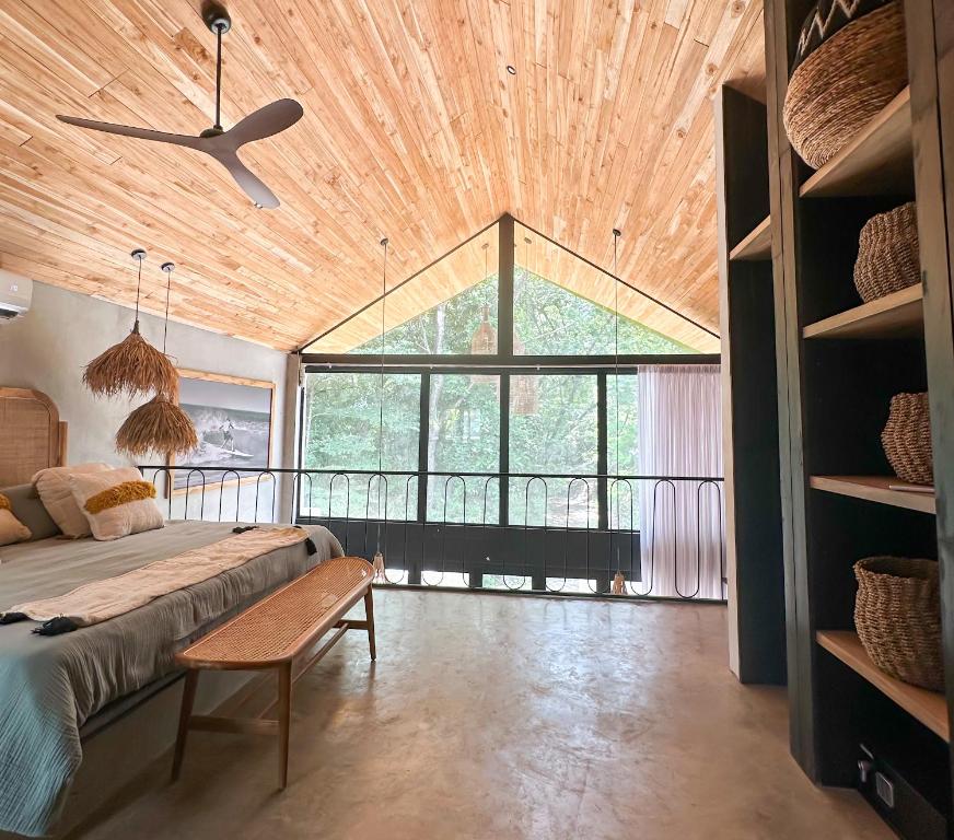 a bedroom with a bed and a large window at Las chozas II in Tamarindo