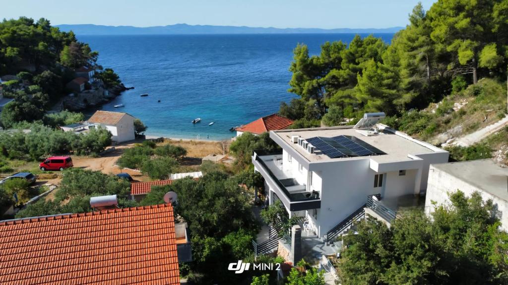a house with solar panels on the roof next to the ocean at Apartmani Bradaric Hvar in Gdinj