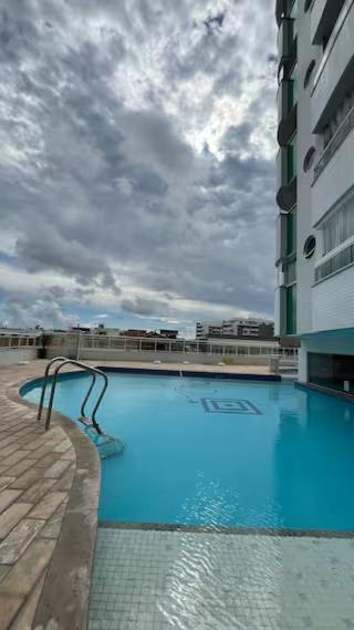 a large swimming pool with a statue in front of a building at Studio Luxuoso in Cabo Frio