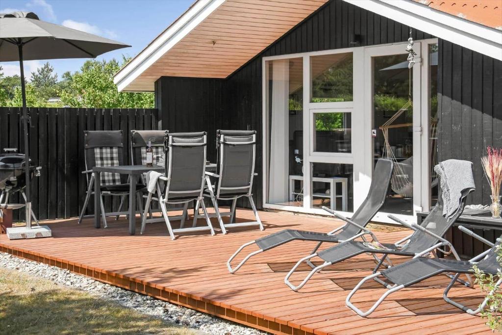 a deck with chairs and an umbrella on a house at C11216-Hemmet-Ildervej-5 in Hemmet