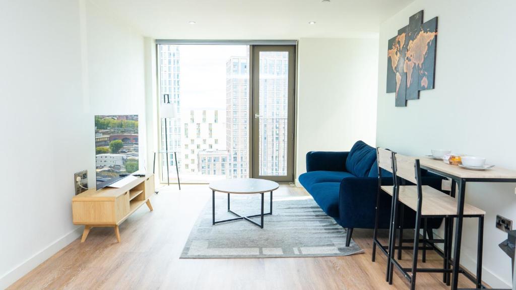 Una sala de estar con un sofá azul y una mesa. en Luxe Apartment in M1 with Pool, Gym & Spa, en Mánchester