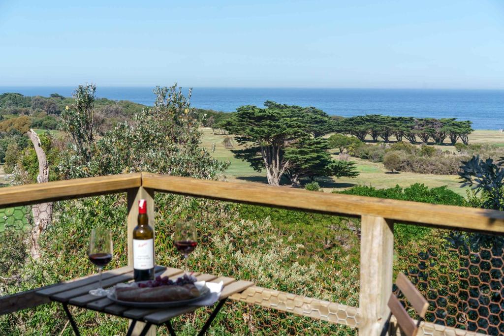 een fles wijn op een tafel met uitzicht op de oceaan bij Cleversley Cottage - Ocean Views Pets Golf in Flinders