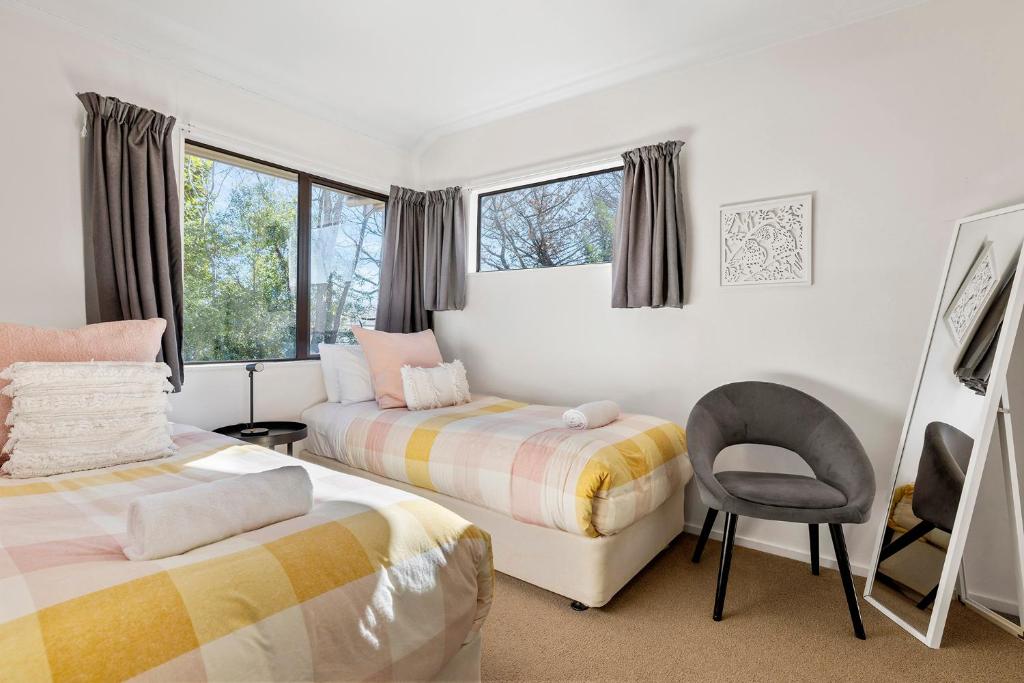 a bedroom with two beds and a chair at The Tuis Nest in Taupo