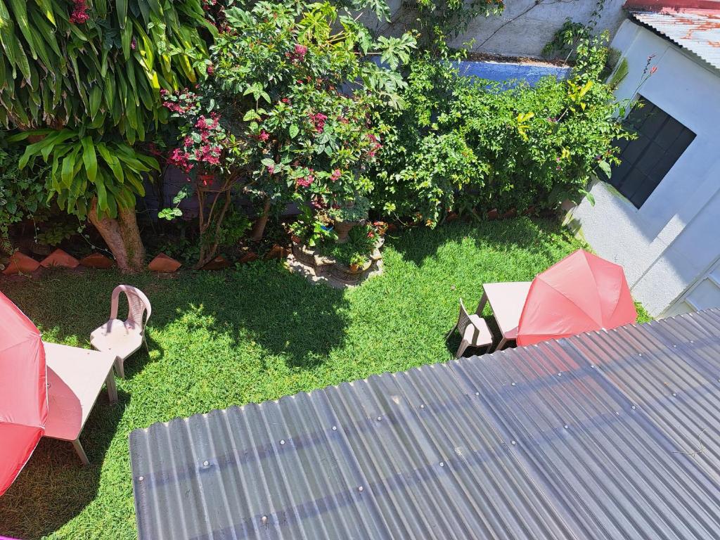a garden with a table and red umbrellas on the grass at Posada Colonial El Buen Pastor in Antigua Guatemala