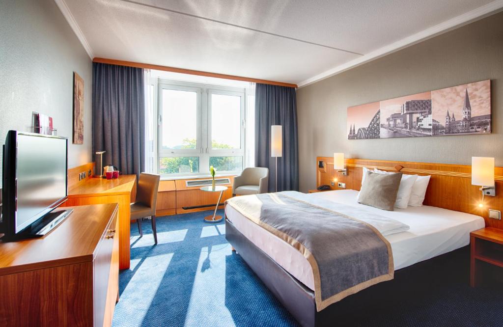 a hotel room with a bed and a television at Leonardo Hotel Köln Bonn Airport in Cologne