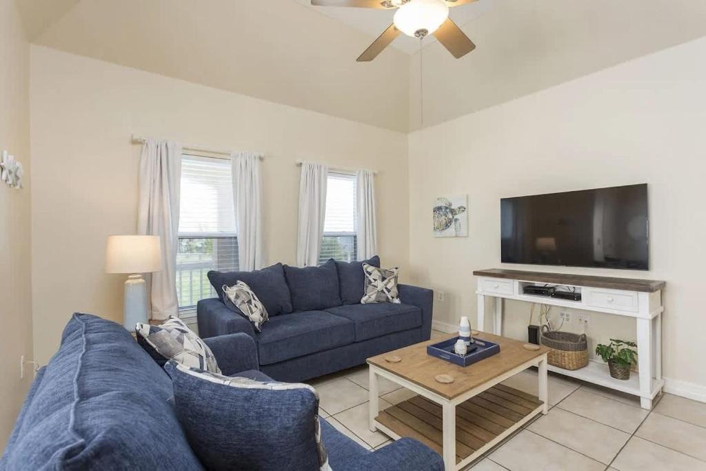 Una sala de estar con un sofá azul y un televisor. en Dom's Beach Retreat home, en South Padre Island