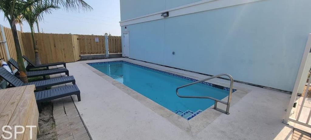 a small swimming pool with two chairs and a fence at Villas de Laguna 3 townhouse in South Padre Island