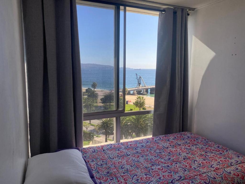 a bedroom with a window with a view of the ocean at Habitación frente a Muelle Vergara en un departamento in Viña del Mar