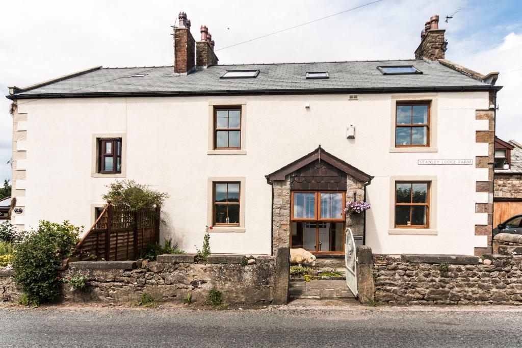 a white house with a stone wall at Stanley Lodge Farmhouse in Cockerham