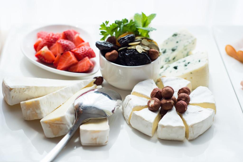 Assorted cheese platter with brie slices topped with hazelnuts, dried fruit and strawberries.