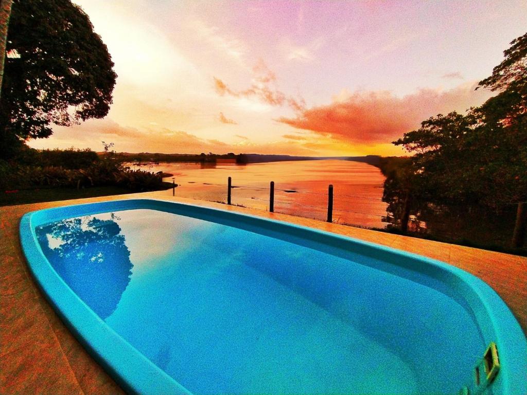 a blue swimming pool with a view of the water at Casa de Temporada Felicidade, 2 Piscinas, 38 Hóspedes, 9 Suítes, 2 Churrasqueiras em Itacaré na Bahia in Itacaré