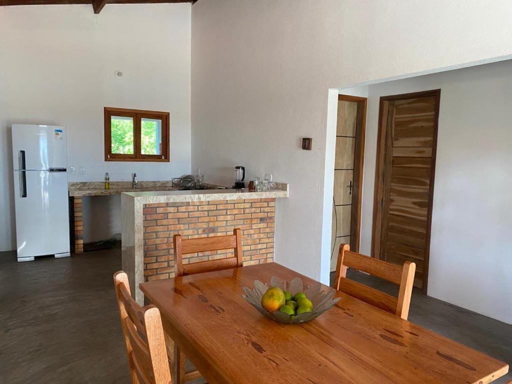 a kitchen with a wooden table with a bowl of fruit on it at Casa Pôr do Sol in Guriú