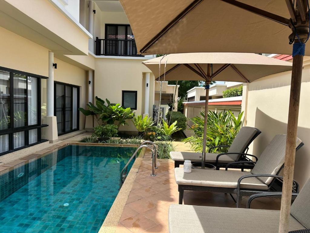 a swimming pool with two chairs and an umbrella at Phuket Laguna 4-Bedrooms XXL Villa And Private Swimming Pool in Ban Thalat Choeng Thale