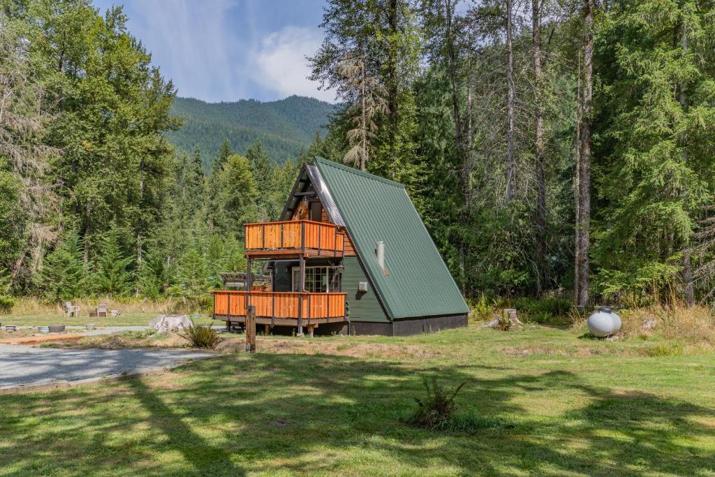 a house with a green roof in the middle of a field at A-Frame At Entrance to Rainier- Hot Tub & WiFi in Ashford