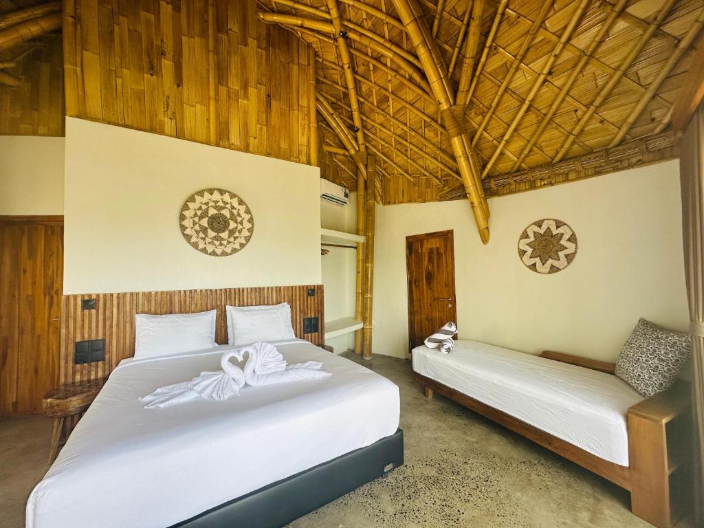 two beds in a room with wooden walls and ceilings at Green Poya Resort and Spa in Selong Belanak