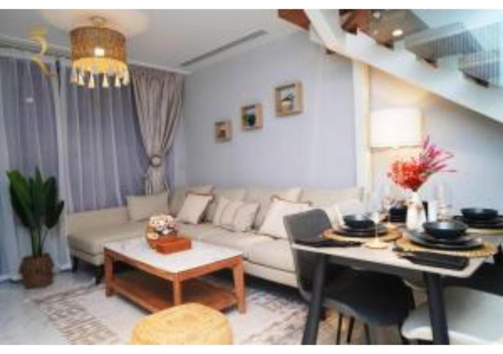 a living room with a couch and a table at Jade Serenity 2BR - Pool, Gym & Comfort Near Masdar Park, Masdar City in Abu Dhabi