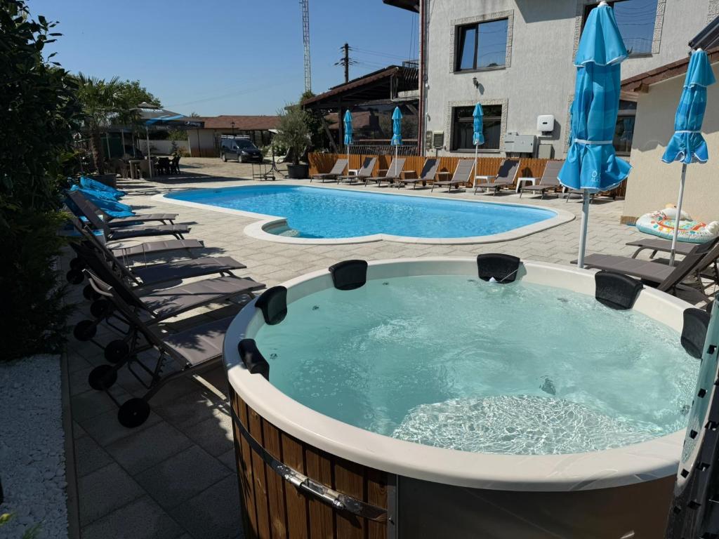 a large hot tub with chairs and umbrellas at Casa di Nobilis in Gheboieni