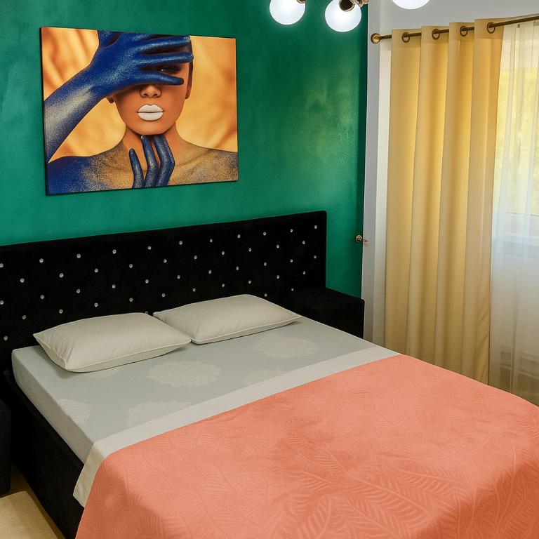 a bedroom with a bed with a painting on the wall at Apartament Justin in Galaţi
