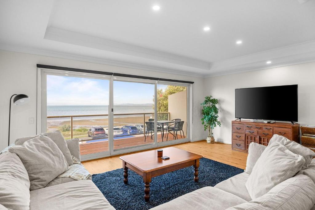 a living room with a couch and a large window at Rhyll Seaside Penthouse in Rhyll