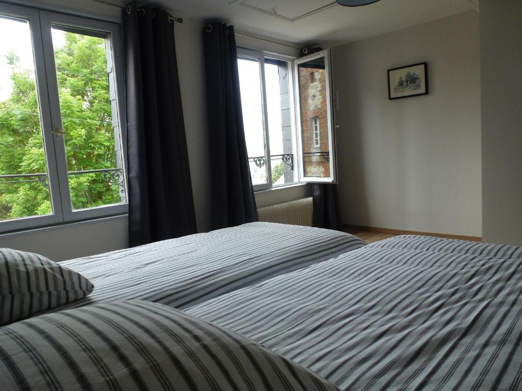 - un lit dans une chambre avec 2 fenêtres dans l'établissement Le charme à la Française, à Honfleur