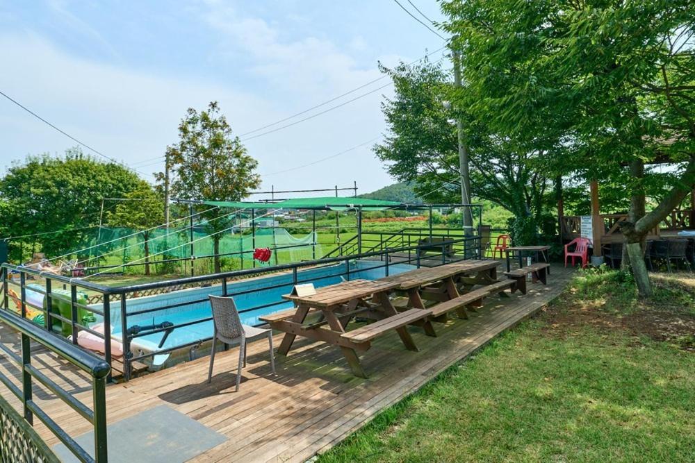 a picnic table and benches next to a pool at Daebudo Batddureong in Ansan
