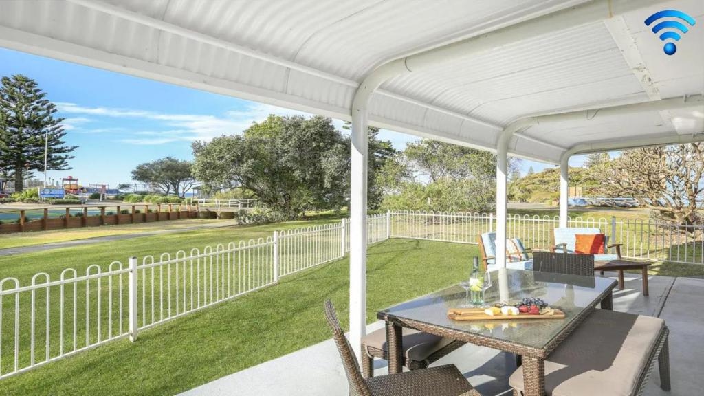 pérgola blanca en un patio con mesa y sillas en Kendalls Two, en Kiama
