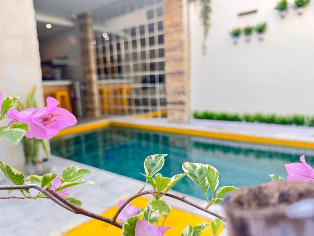 a plant with pink flowers next to a swimming pool at Palm Villa 5 Seminyak Center in Seminyak