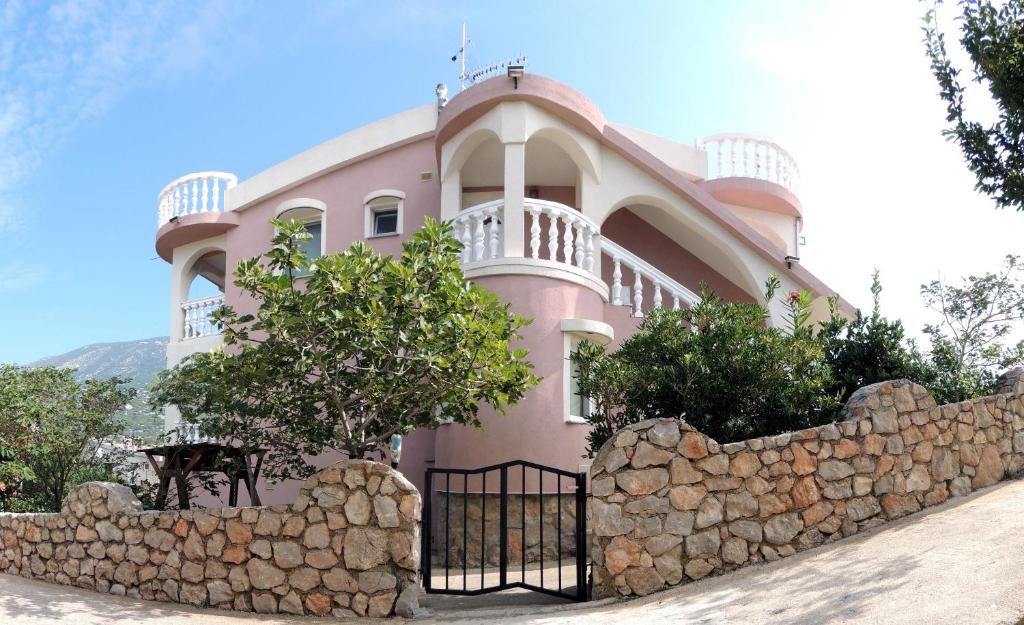 a large pink house behind a stone wall at Tea-Dream house in Cesarica