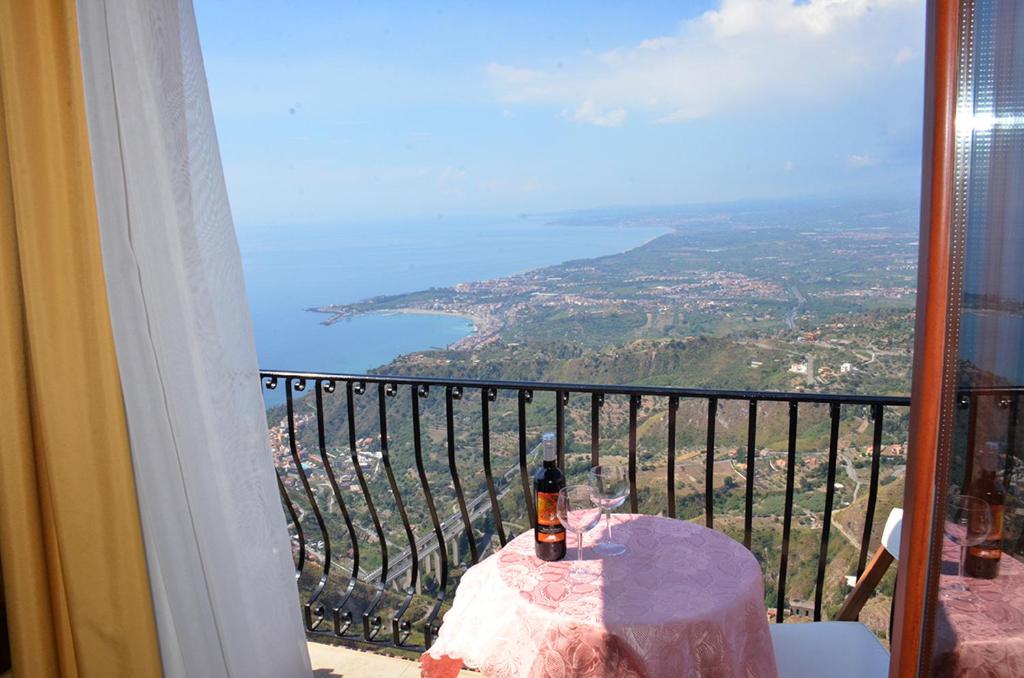 a bottle of wine sitting on a table on a balcony at B&B Casa Bellavista in Castelmola