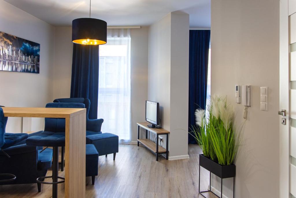 a living room with blue chairs and a television at Apartament Paryski CENTRUM #nestapartamenty in Bielsko-Biala