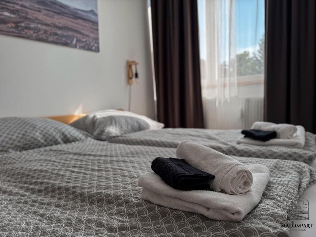two beds with towels on them in a hotel room at Malompart Apartman in Tapolca