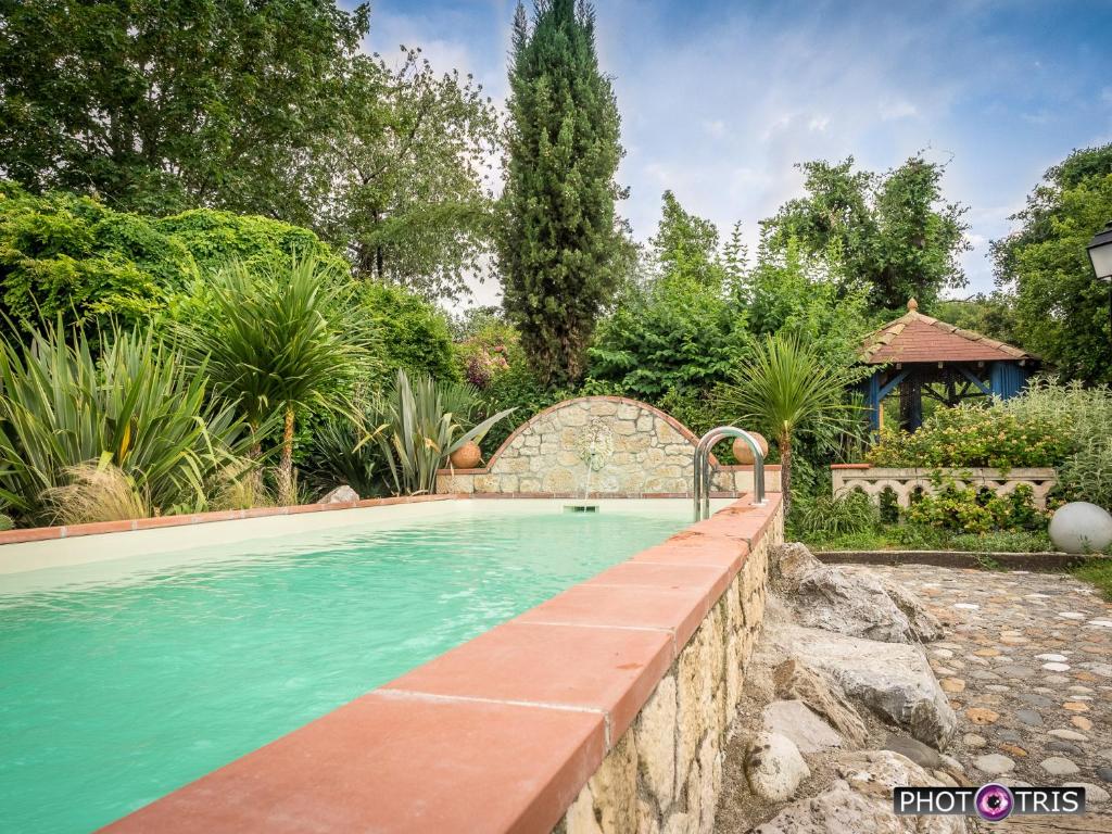 a swimming pool in a yard with a stone retaining wall at La Maynade in Loubens-Lauragais