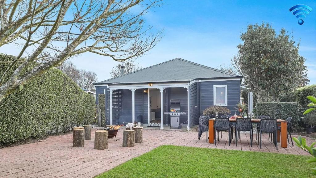 een klein huisje met een tafel en stoelen in een tuin bij Coachwood Cottage in Robertson