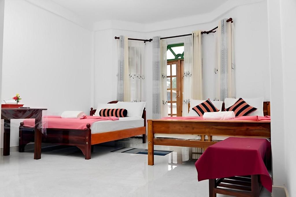 a bedroom with two beds and a table at Malaka Inn Bandarawela in Bandarawela