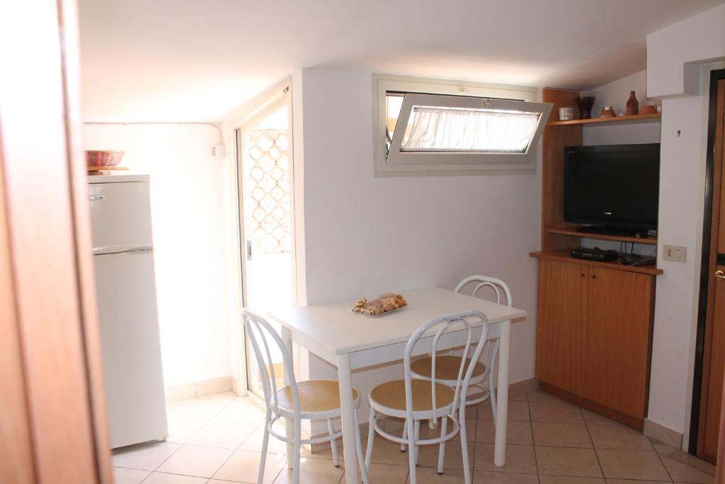 uma pequena cozinha com uma mesa branca e cadeiras em Mansarda 25 em Terracina