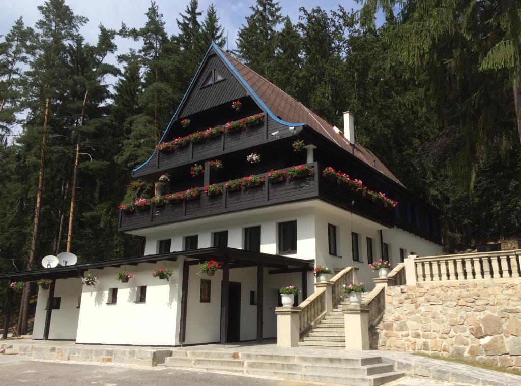 a white building with flower boxes on the roof at Hunting Lodge Vitkov in Sokolov