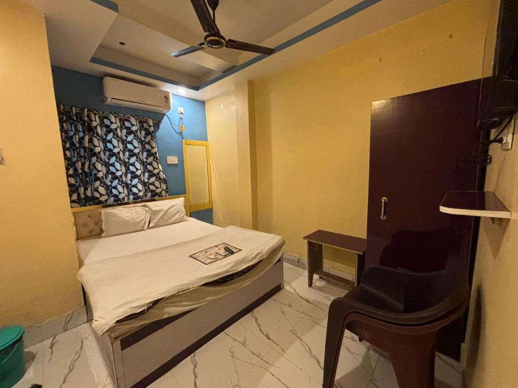 Un pequeño dormitorio con una cama y una silla. en Hotel Sunset Park, en Calcuta