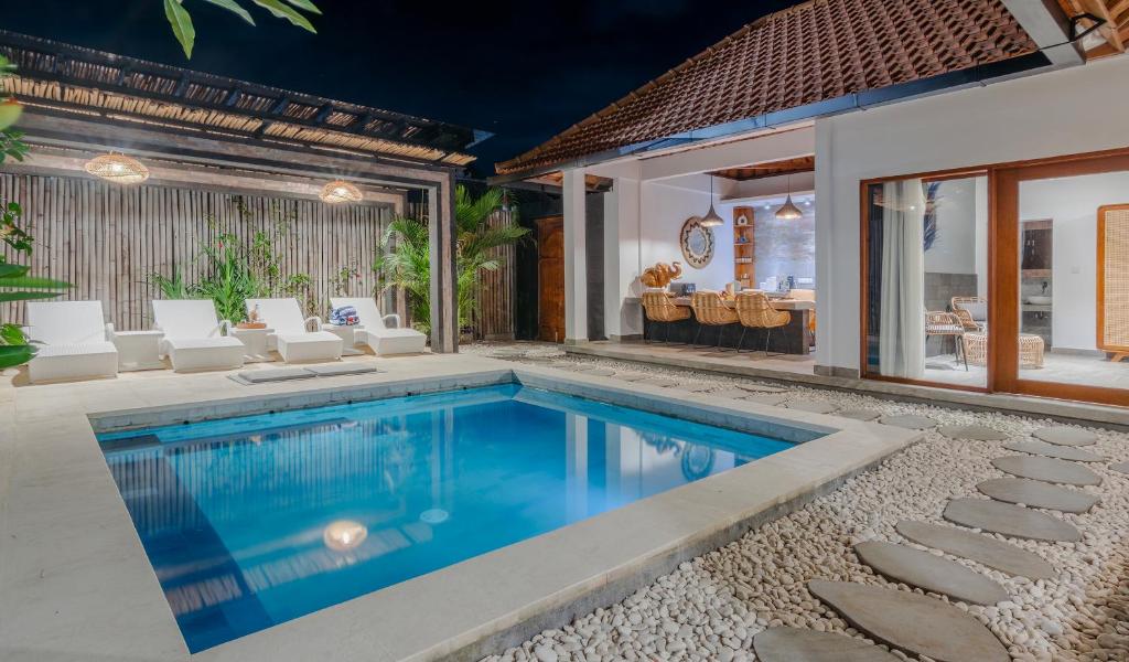an indoor pool with white chairs and a house at Villa Dunia Lembongan in Nusa Lembongan