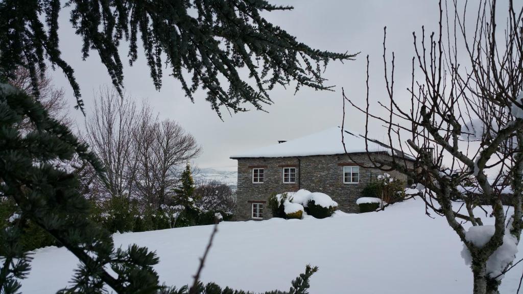 a house with a pile of snow in front of it at A Lareira in Chan de Vilar