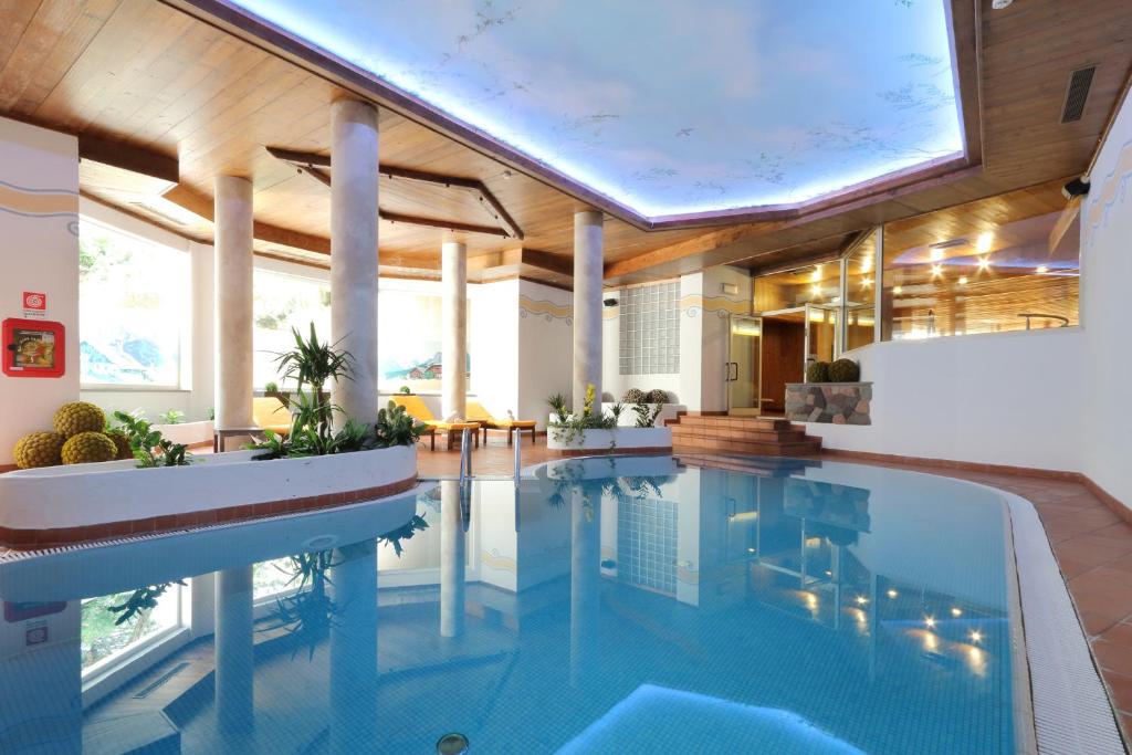 una piscina in una casa con un grande soffitto di Park Hotel Bellacosta a Cavalese