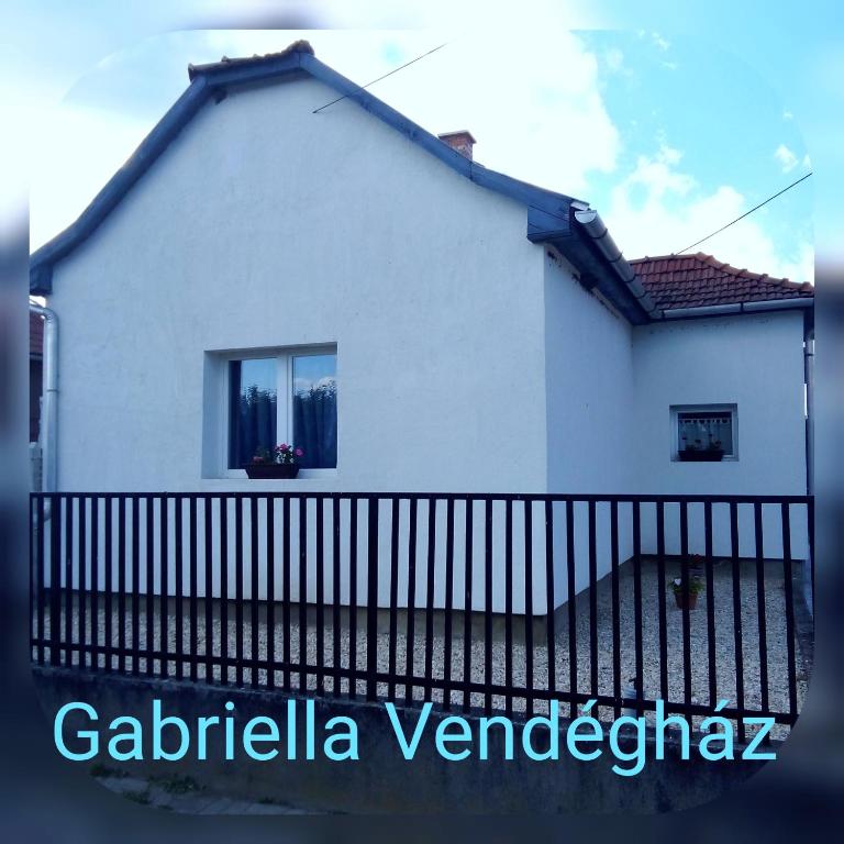 a white house with a black fence at Gabriella Vendégház in Vadna