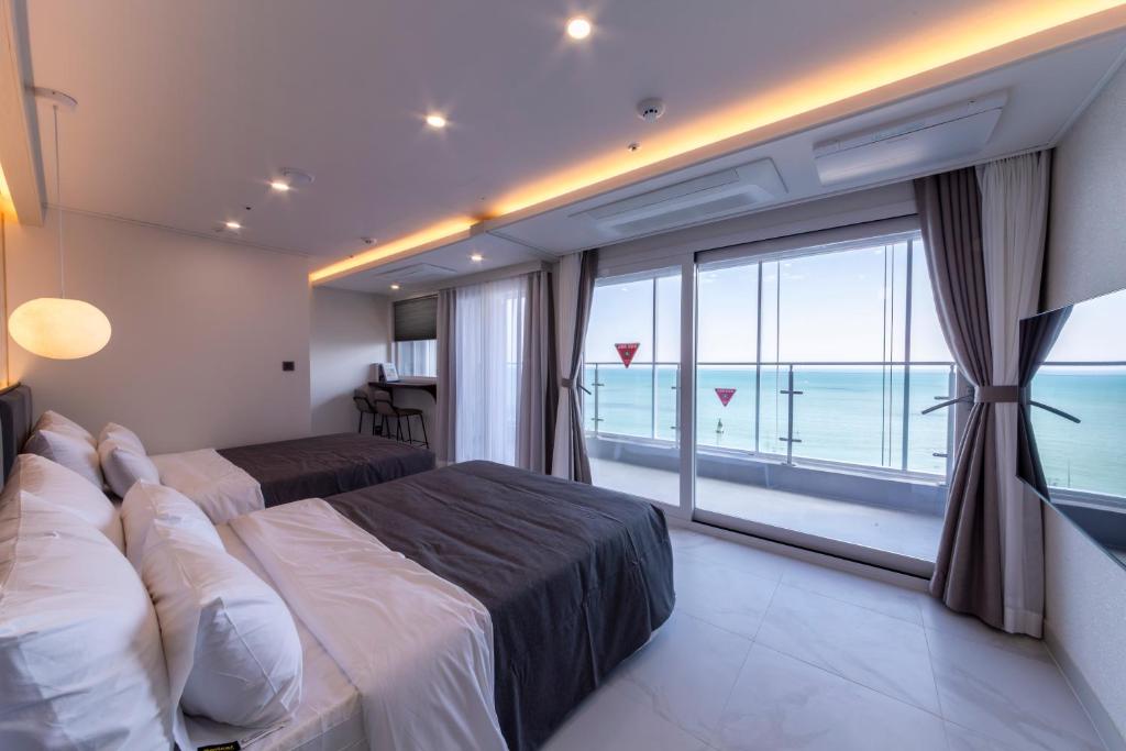 a bedroom with a bed and a large window with the ocean at Raviens Maison de Hotel in Busan