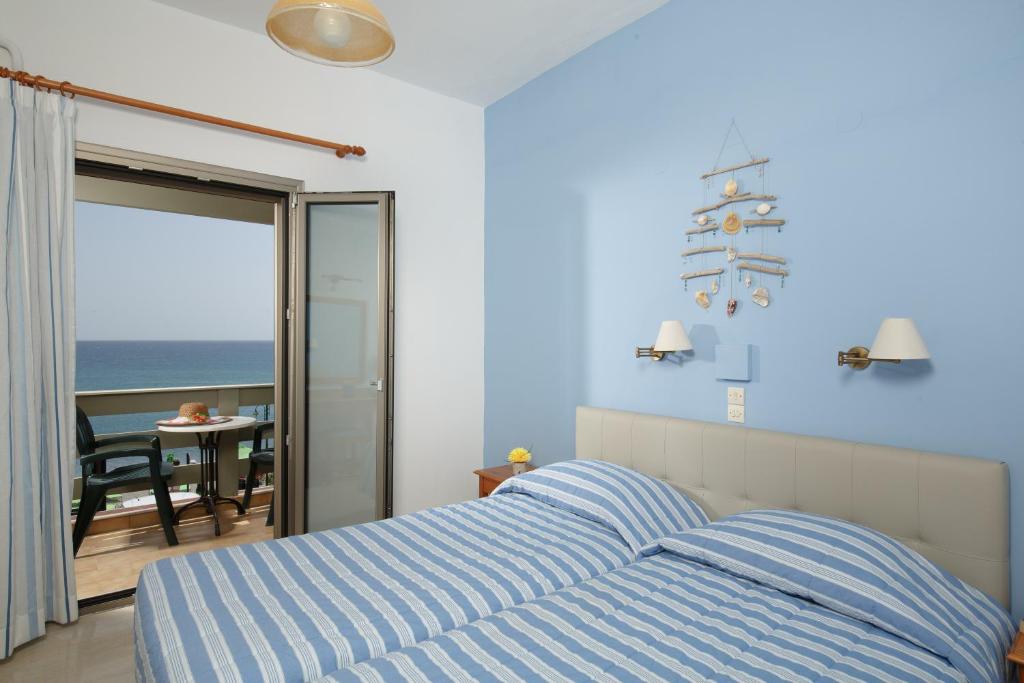 a bedroom with a bed and a view of the ocean at Flisvos Rooms in Plakias