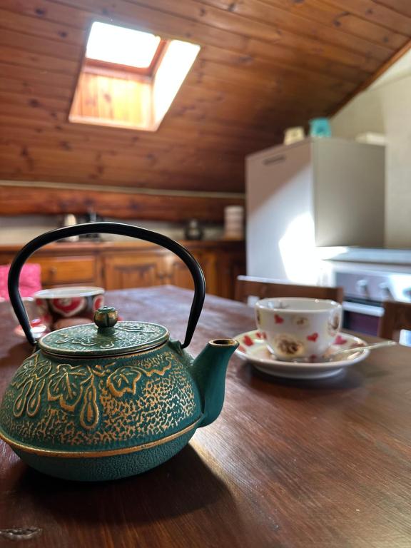 Una tetera verde sobre una mesa de madera con una taza en L'Atelier du Temps - Le Nid, en Aosta