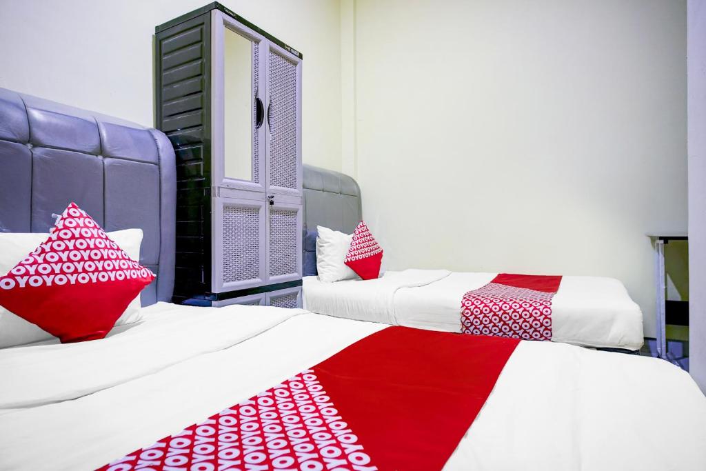 Una habitación con dos camas con sábanas rojas y blancas. en Hotel O Balige City Near Tugu Juara Monang, en Balige