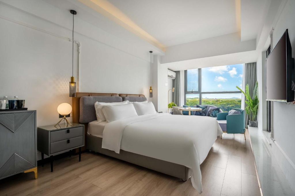 三亜市にあるMin Xiangmi Design Residence (Sanya Bay Phoenix International Airport Store)の大きな白いベッドと大きな窓のある寝室