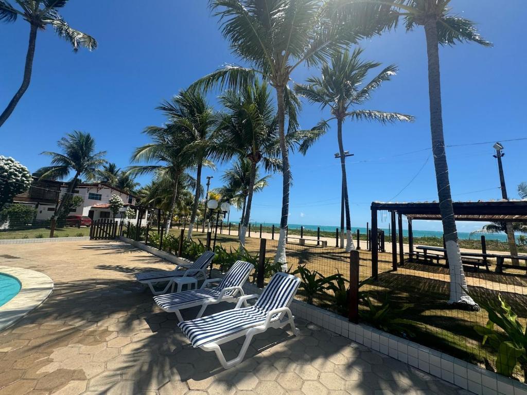 - deux chaises et des palmiers à côté de la plage dans l'établissement Casa Privê Maragogi 26 - Pé na areia, à Maragogi