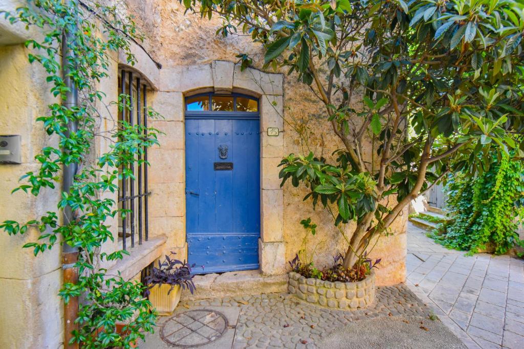 a blue door on the side of a building with a tree at Maison Maples- Le charme provençal in Villecroze