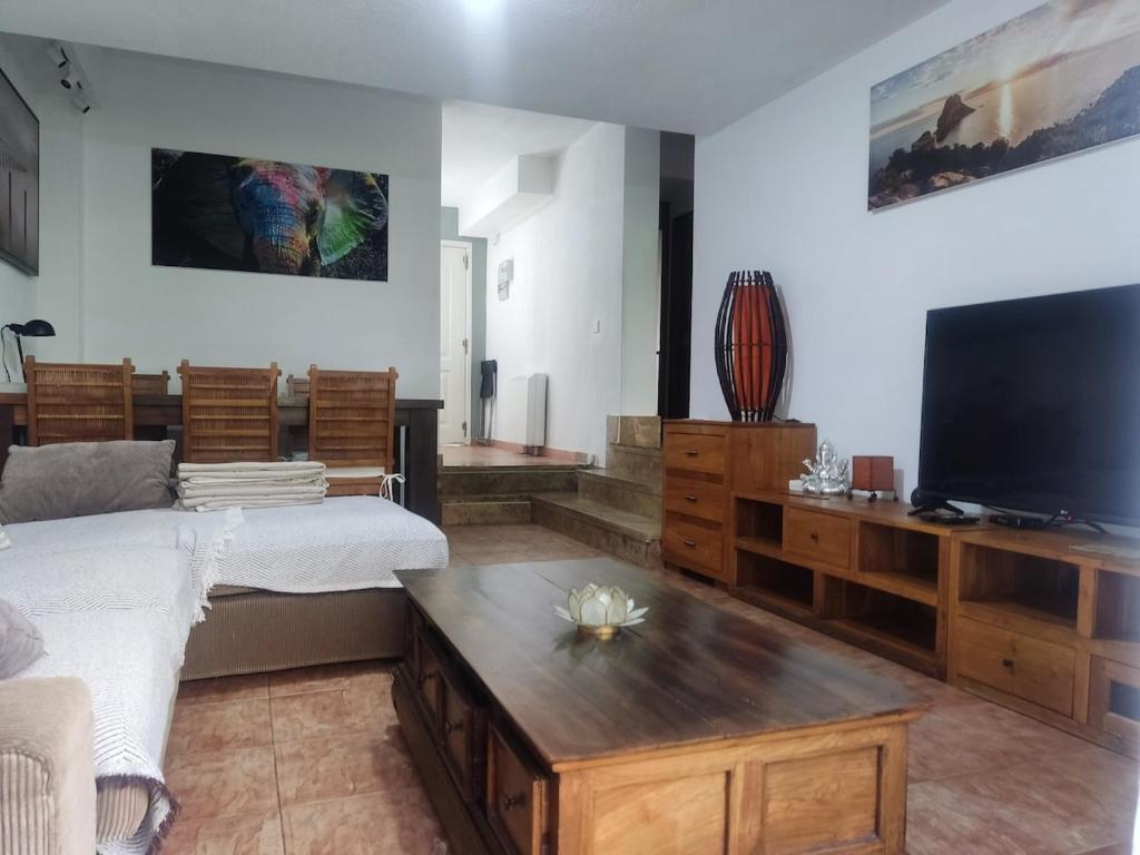 sala de estar con cama y TV de pantalla plana en apto 2 hab y jardín cerca de Alcalá de Henares, en Villalbilla