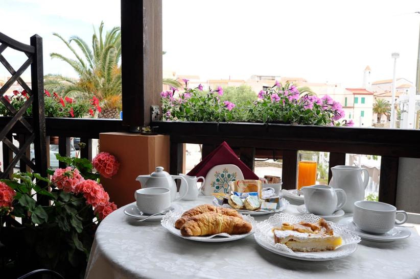 un tavolo con piatti di cibo, tazze e croissant di Lina Hotel a Stintino
